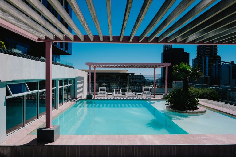 Rooftop swimming pool with lounge chairs overlooking a city skyline at a luxury residential building