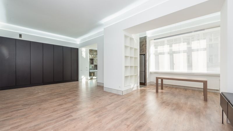 Bright empty room with hardwood flooring and sunlight from large windows