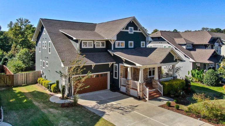 Craftsman-style house with a gray roof, wide front porch and trimmed lawn