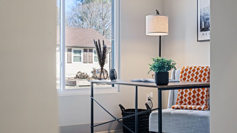 Bright home office with a minimalist desk, lamp, and blanket by a window