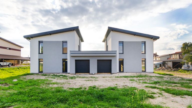 Two modern twin houses with matching rooflines and clean lines under an overcast sky