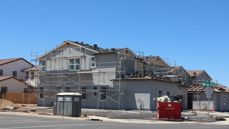 New houses under construction with scaffolding and wood framing in a suburban development