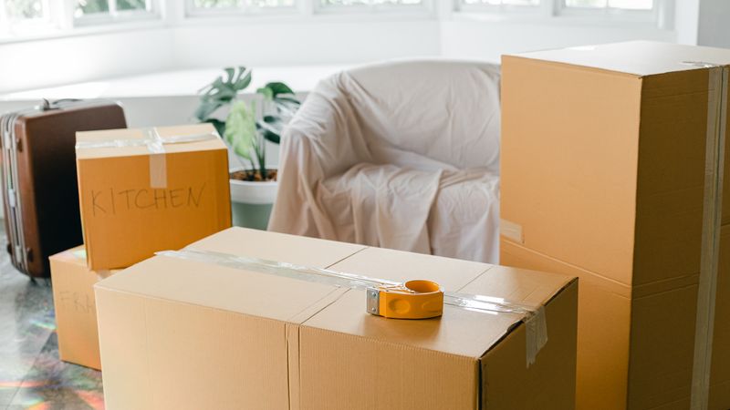 Packed cardboard boxes in a bright empty living room before a move