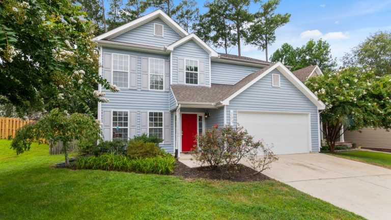 Two-story suburban house with a trimmed lawn and flower garden in front