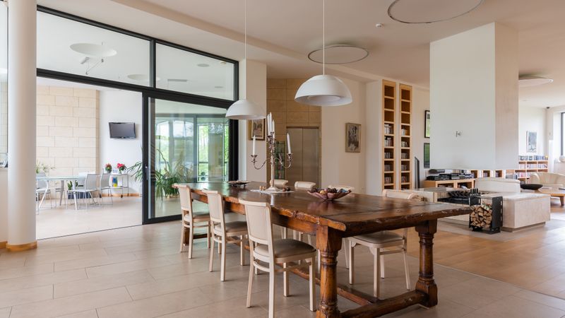 Wooden dining table with chairs and hanging lamps beside an open doorway to a terrace