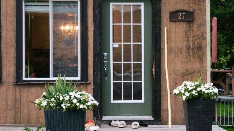 Rustic wooden house entrance with large potted flowers by the door