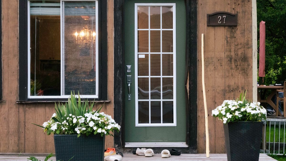 Rustic wooden house entrance with large potted flowers by the door